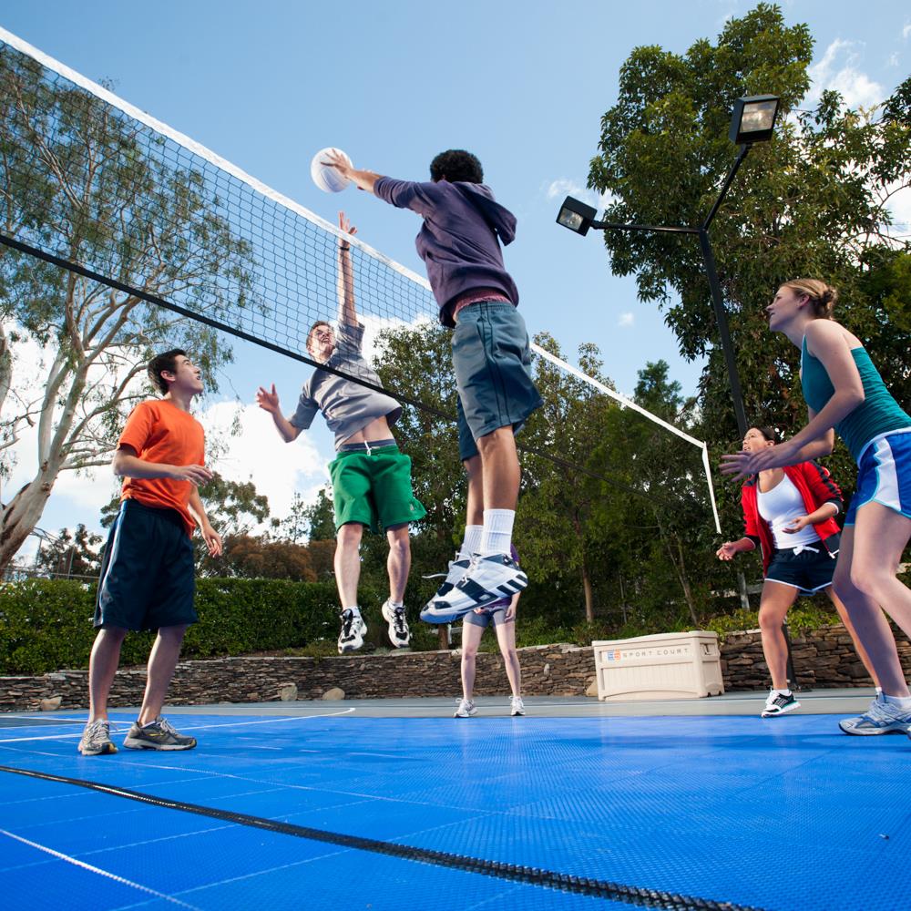 group of kids playing volleyball on outdoor sport court surface